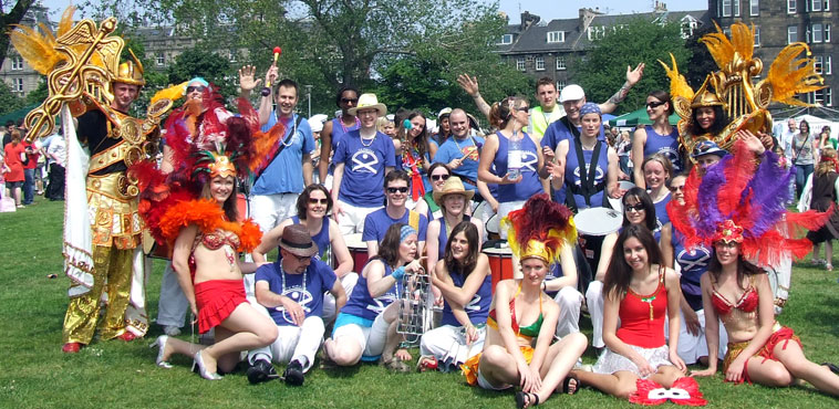 Group photo of the Embra Samba School with a Festival Steward waving in the background